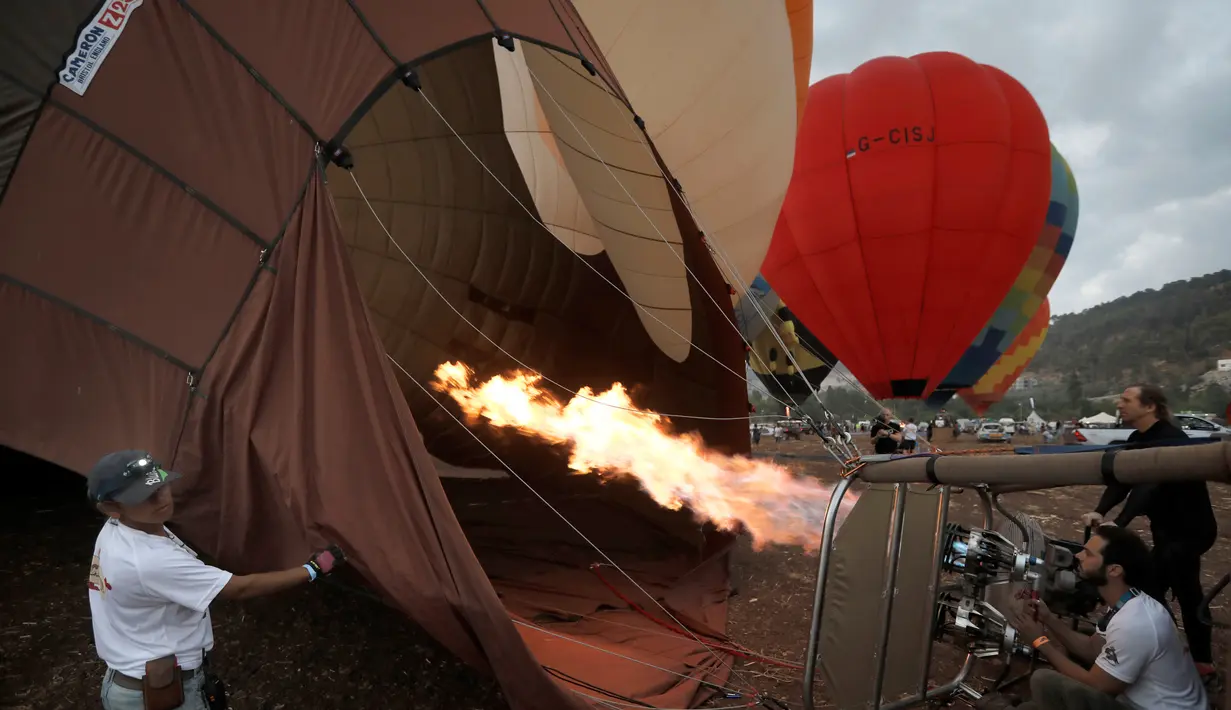 Peserta mempersiapkan balon udaranya sebelum mengikuti Festival Balon Udara Gilboa di dekat Kibbutz Ein Harod, Lembah Jizreel, Israel (4/8). Festival balon udara ini menjadi tontonan menarik bagi warga sekitar dan wisatawan. (AFP Photo/Manahem Kahana)