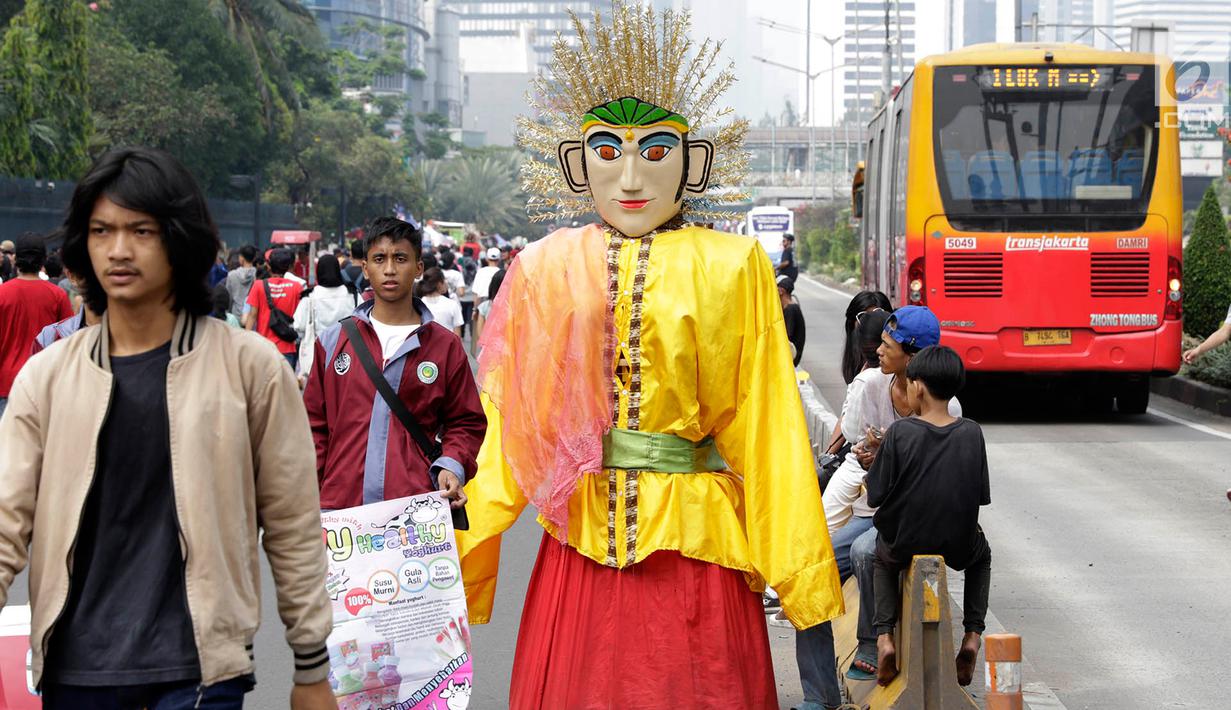 Pengamen ondel-ondel meminta sumbangan kepada warga di lokasi car free day, Jakarta, Minggu (21/5). Seiring berjalannya waktu, ondel-ondel kini dimanfaatkan oleh warga Jakarta untuk mencari nafkah. (Liputan6.com/Immanuel Antonius)