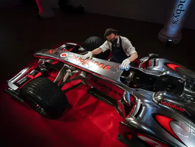 Staf memoles mobil McLaren MP4-25A Mercedes yang dikendarai Lewis Hamilton pada GP Turki 2010, di Sotheby London, Selasa (18/5/2021). Mobil yang pernah membawa Hamilton menjadi juara dunia pada 2010 itu diperkirakan akan laku sekitar Rp 71,5 miliar hingga Rp 100 miliar. (AP Photo/Alberto Pezzali)