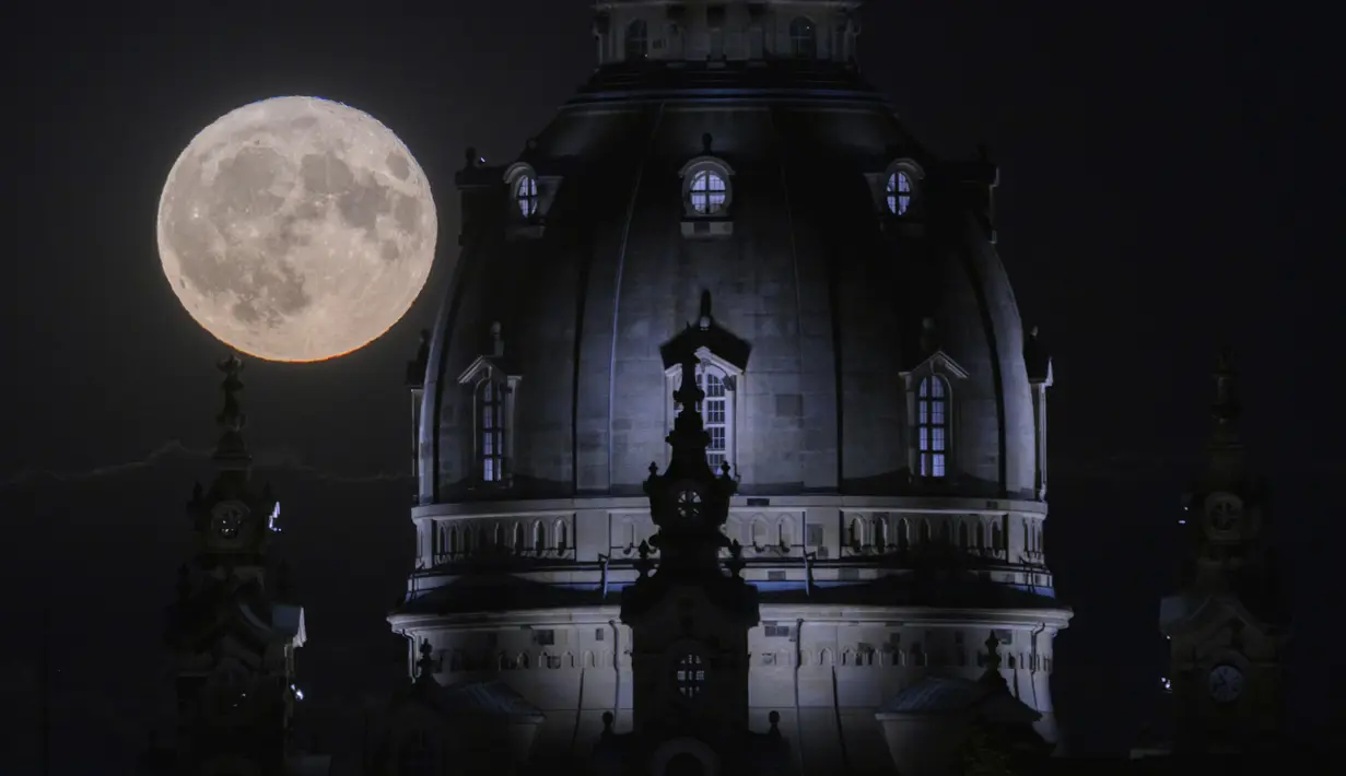Bulan penuh yang disebut sebagai Buck Moon terbit di sore hari di langit di belakang Frauenkirche, di Dresden, Jerman, Senin, 3 Juli 2023. (Robert Michael/dpa via AP)