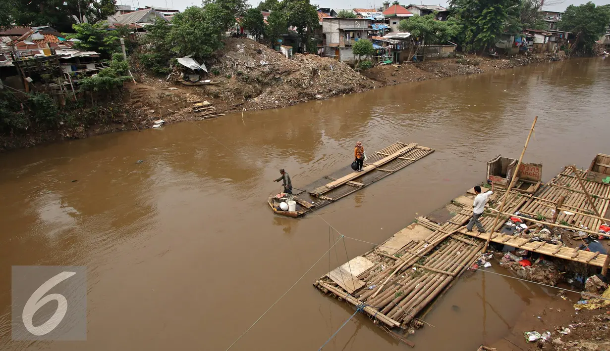 Warga saat menyebrangi Kali Ciliwung mengunakan eretan, Jakarta, Senin (30/11). Tidak adanya fasilitas jembatan menyebabkan warga memilih eretan sebagai sarana penyeberangan sehari-hari, meskipun dengan kondisi seadanya. (Liputan6.com/Immnuel Antonius)