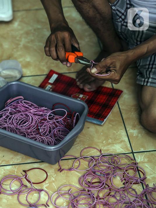 Seorang anak membuat serokan ikan cupang di rumah kontrakan Udin, Sukabumi Selatan, Jakarta Barat, Selasa (22/12/2020). Dalam sehari, Udin sanggup membuat serokan ikan cupang sebanyak 400 buah. (Liputan6.com/Johan Tallo)