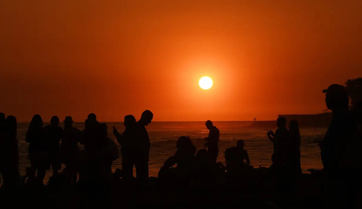 Sejumlah orang bermain di pantai El Tunco saat matahari terbenam di La Libertad, 34 km sebelah selatan dari San Salvador, pada 5 Maret 2017.  (AFP Photo / Marvin Recinos)