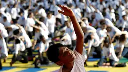 Seorang bocah melakukan gerakan yoga saat berlatih di Lapangan Independen di Kuala Lumpur, Malaysia (2/7). Acara yoga bersama ini bertemakan 'Yoga for Harmony & Peace'. (AP Photo / Daniel Chan)