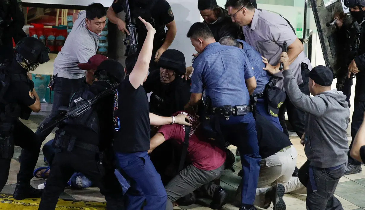 Polisi menangkap pelaku penyenderaan Alchie Paray saat sedang berbicara kepada awak media di V-Mall, Manila, Filipina, Senin (2/3/2020). Pernyataan singkat Alchie Paray kepada awak media mendapat pujian warga sekitar yang hadir untuk menyaksikan proses penyanderaan. (AP Photo/Aaron Favila)