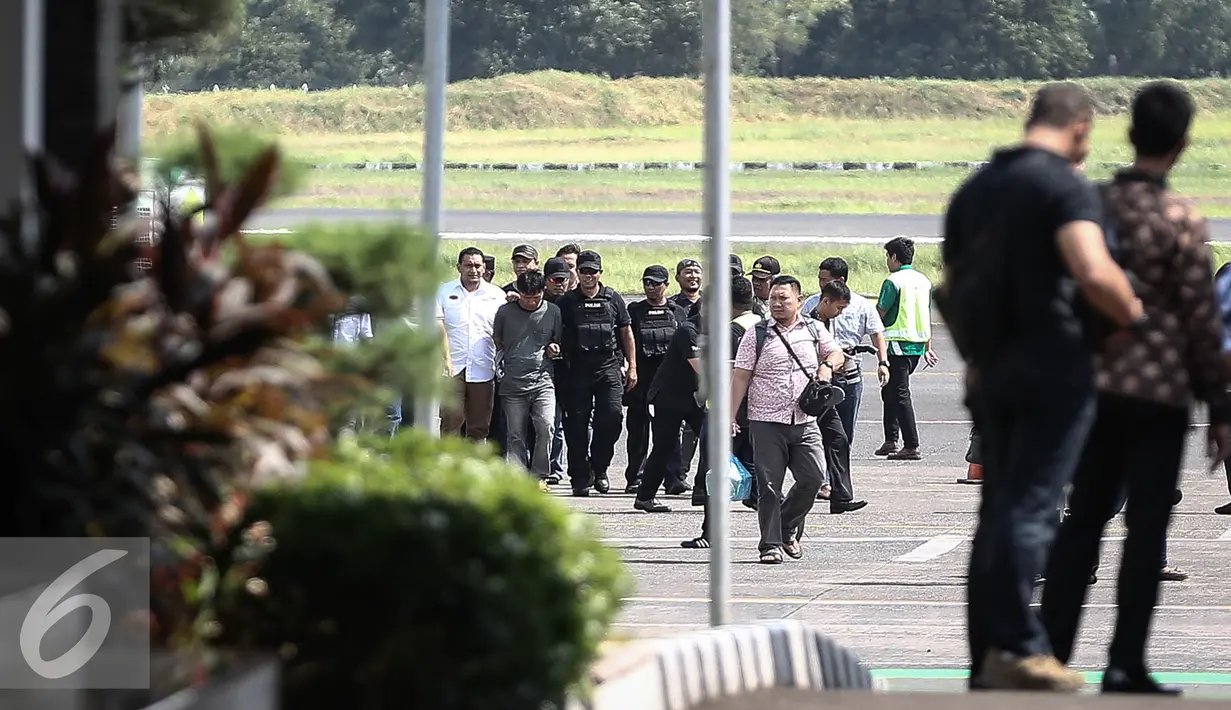 Petugas kepolisian membawa tersangka pembunuhan dan perampokan Pulomas Ridwan Sitorus alias Pius Pane saat tiba di Bandara Halim Perdana Kusuma, Jakarta, Minggu (1/1). (Liputan6.com/Faizal Fanani)