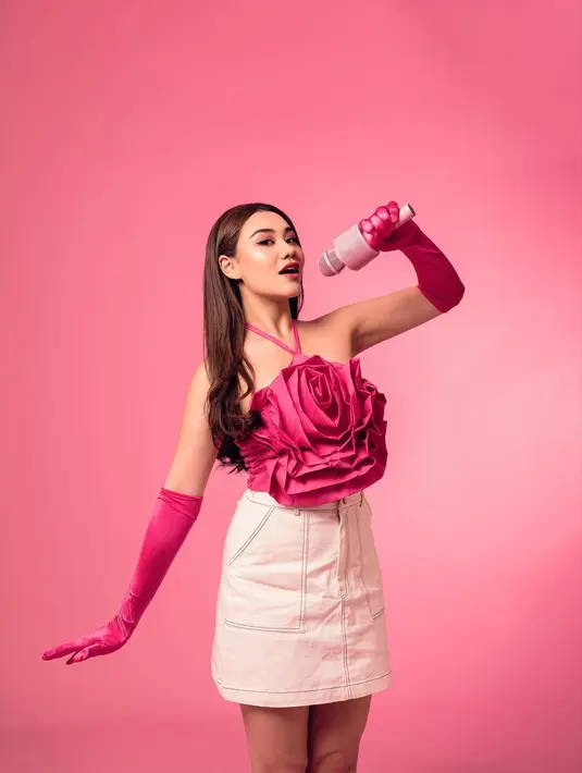 Lihat Aaliyah Massaid mendandani dirinya bak boneka Barbie. Dengan atasan berbentuk bunga berwarna pink, detail halter-neck, Aaliyah tampil manis memadukannya dengan mini skirt putih, gloves lateks berwarna pink senada dengan atasannya. [Foto: Instagram/aaliyah.massaid]