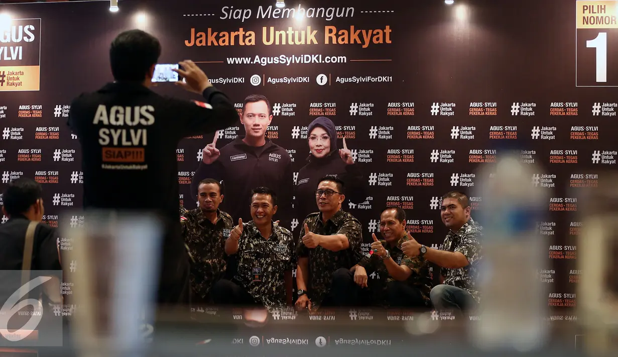 Simpatisan pasangan Cagub DKI Jakarta Agus Harimurti Yudhoyono dan Silviana Murni berfoto dengan latarbelakang Pasangan Calon nomer urut 1 di Hotel Dharmawangsa, Jakarta Selatan, Sabtu (11/12). (Liputan6.com/Johan Tallo)