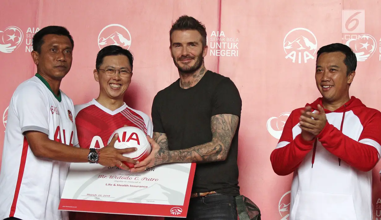 Mantan bintang sepak bola Inggris David Beckham memberikan bola kepada pelatih sepak bola Widodo C Putra didampingi Menpora Imam Nahrawi dan Presdir AIA Ben Ng pada AIA Sepak Bola untuk Negeri di Jakarta, Minggu (25/3). (Liputan6.com/Herman Zakharia)