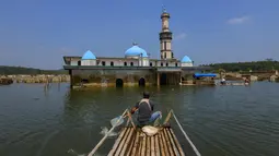 Warga menggunakan perahu menyaksikan puing-puing bangunan mesjid dan rumah yang kembali muncul di kawasan Bendungan Karian yang mengering di Kampung Somang, Lebak, Banten, Jumat, 7 Agustus 2026. (KLY/ Arie Basuki)