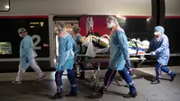 Petugas medis membawa pasien virus corona COVID-19 di Stasiun Gare d'Austerlitz di Paris, Prancis, Rabu (1/4/2020). Prancis mengerahkan kereta kecepatan tinggi untuk mengevakuasi pasien COVID-19 dari Paris ke wilayah Brittany. (Thomas SAMSON/AFP/POOL)