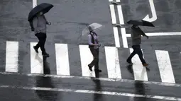 Orang-orang berjalan di tengah hujan saat Topan Mindulle di Tokyo, Jepang, Jumat (1/10/2021). Topan Mindulle sedang bergerak di lepas pantai Jepang. (AP Photo/Eugene Hoshiko)