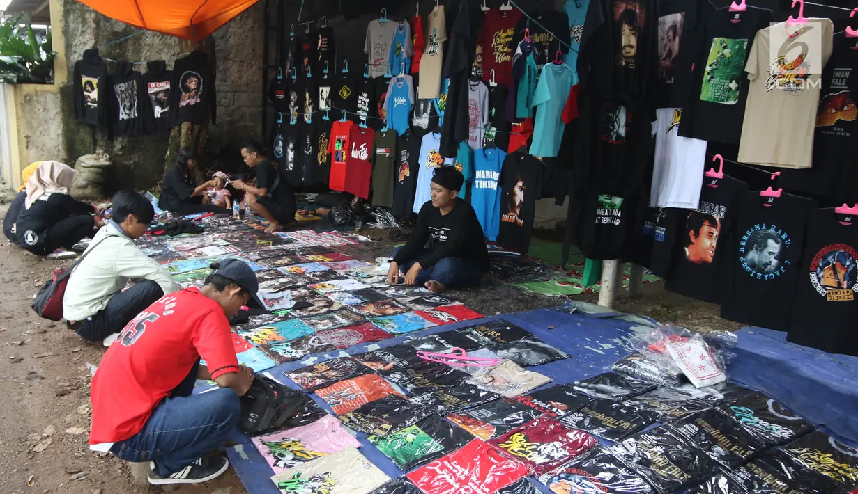 Penggemar Iwan Fals memilih kaos yang dijajakan pedagang di luar lokasi Konser Situs Budaya, kawasan Depok, Jawa Barat, Sabtu (3/3). Dalam Konser kali ini, Iwan Fals dan Band berkolaborasi dengan beberapa musisi. (Liputan6.com/Arya Manggala)