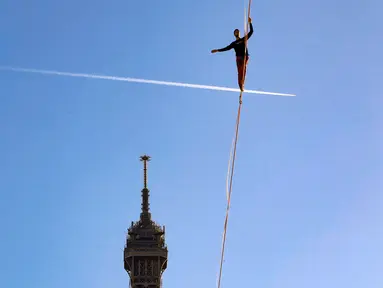Seniman trapeze, Nathan Paulin berjalan di seutas tali ketika melakukan slackline dari Menara Eiffel menuju alun-alun Trocadero di Paris, 9 Desember 2017. Aksi menegangkan itu dilakukan dengan ketinggian sekitar 200 kaki. (JACQUES DEMARTHON/AFP)