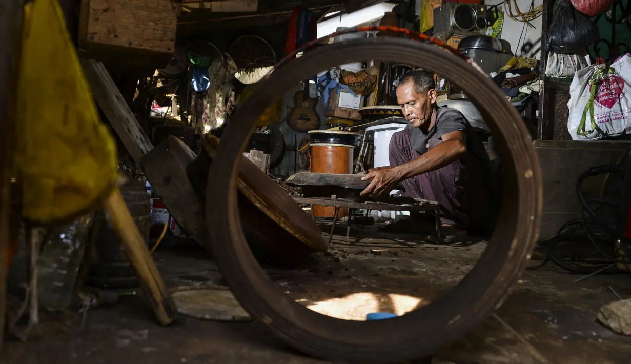 Pembuat rebana tradisional, Fajar Siddiq, yang kehilangan pekerjaan karena pandemi Covid-19, bekerja di rumahnya di Lambaro, Provinsi Aceh, Senin (22/2/2021). Usaha produksi berbagai jenis alat musik tradisional Aceh berupa rapai, serune kale dan seruling mulai langka. (CHAIDEER MAHYUDDIN / AFP)