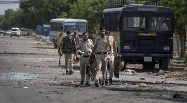 Pecahan kaca dan puing-puing berserakan di jalan saat polisi berpatroli setelah bentrokan komunal di Nuh di negara bagian Haryana, India, Selasa, 1 Agustus 2023. (AP Photo/Altaf Qadri)