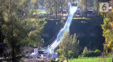 Pekerja menyelesaikan finishing jembatan kaca Seruni Point di Pasuruan, Jawa Timur, Minggu (30/4/2023). Jembatan kaca yang membentang sepanjang 120 meter dengan lebar 1,8 meter di atas jurang dengan kedalaman 80-100 meter ini diperkirakan dapat digunakan wisatawan pada Oktober nanti. (merdeka.com/Arie Basuki)