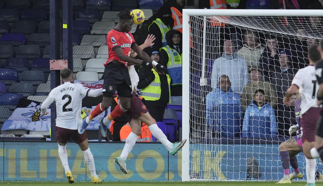 Striker Luton Town, Elijah Adebayo (atas) melepaskan sundulan yang menghasilkan gol ke gawang Manchester City pada laga pekan ke-16 Liga Inggris 2023/2024 di Kenilworth Road, Luton, Minggu (10/12/2023) malam WIB. (AP Photo/Kin Cheung)
