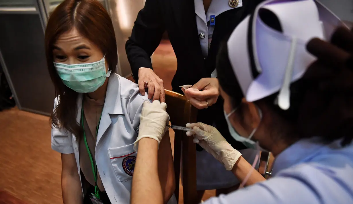 Seorang petugas kesehatan menerima vaksin Covid-19 CoronaVac dari Sinovac, di Institut Penyakit Menular Bamrasnaradura di Bangkok, Minggu (28/2/2021). Meski tertinggal diantara negara-negara Asia Tenggara lainnya, akhirnya Thailand memulai kampanye vaksin COVID-19. (Lillian SUWANRUMPHA/AFP)