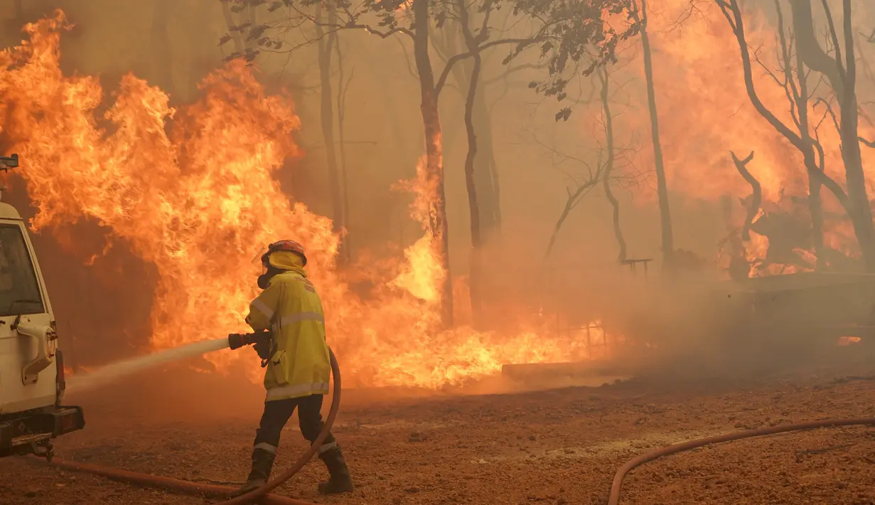 Seorang petugas pemadam kebakaran menangani kobaran api di dekat Wooroloo, timur laut Perth, Australia, Selasa (2/1/2021). Asap dan api dari kebakaran hutan membakar kota terbesar keempat di Australia ini, di tengah pemberlakuan lockdown virus corona COVID-19. (Evan Collis/DFES via AP)