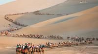 Para wisatawan menaiki unta di padang pasir di Dunhuang di provinsi Gansu di China barat laut (10/8/2019). Dunhuang adalah sebuah kota tingkat kabupaten di barat laut provinsi Gansu, Tiongkok Barat. (AFP Photo/Str)