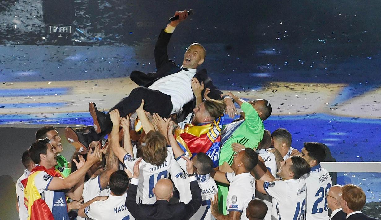 Pemain mengangkat pelatih Real Madrid, Zinedine Zidane, saat merayakan keberhasilan meraih gelar ke-12 Liga Champions di Stadion Santiago Bernabeu, Madrid, Spanyol (4/6). Real Madrid menjadi juara usai mengalahkan Juventus 4-1. (EPA/Fernando Villar)