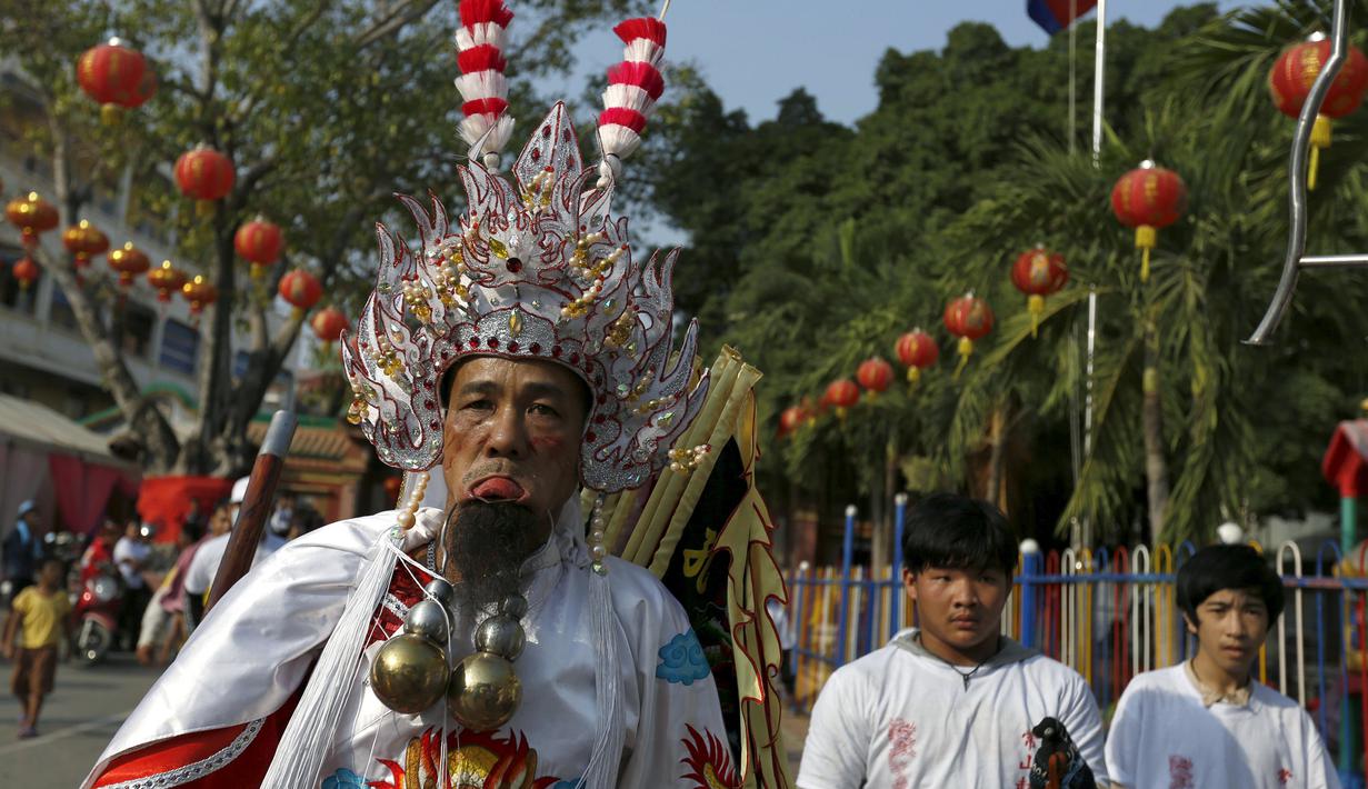 Seorang pria mengenakan kostum unik dengan kail tajam yang menembus pipinya dalam acara Hei Neak Ta atau parade roh untuk memperingati Cap Go Meh, Kamboja, (21/2). Cap Go Meh merupakan rangkaian acara dari tahun baru Imlek. (REUTERS/Samrang Pring) 	