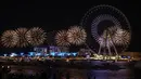 Kembang api menerangi langit selama upacara pembukaan Dubai Eye, yang dikenal sebagai Ain Dubai, di kota Emirat, dekat Dubai Marina, Kamis (21/10/2021). Dubai Eye memiliki tinggi 250 meter dan mampu menampung 1750 pengunjung dalam satu kali rotasi yang berlangsung 30 menit. (Giuseppe CACACE / AFP)