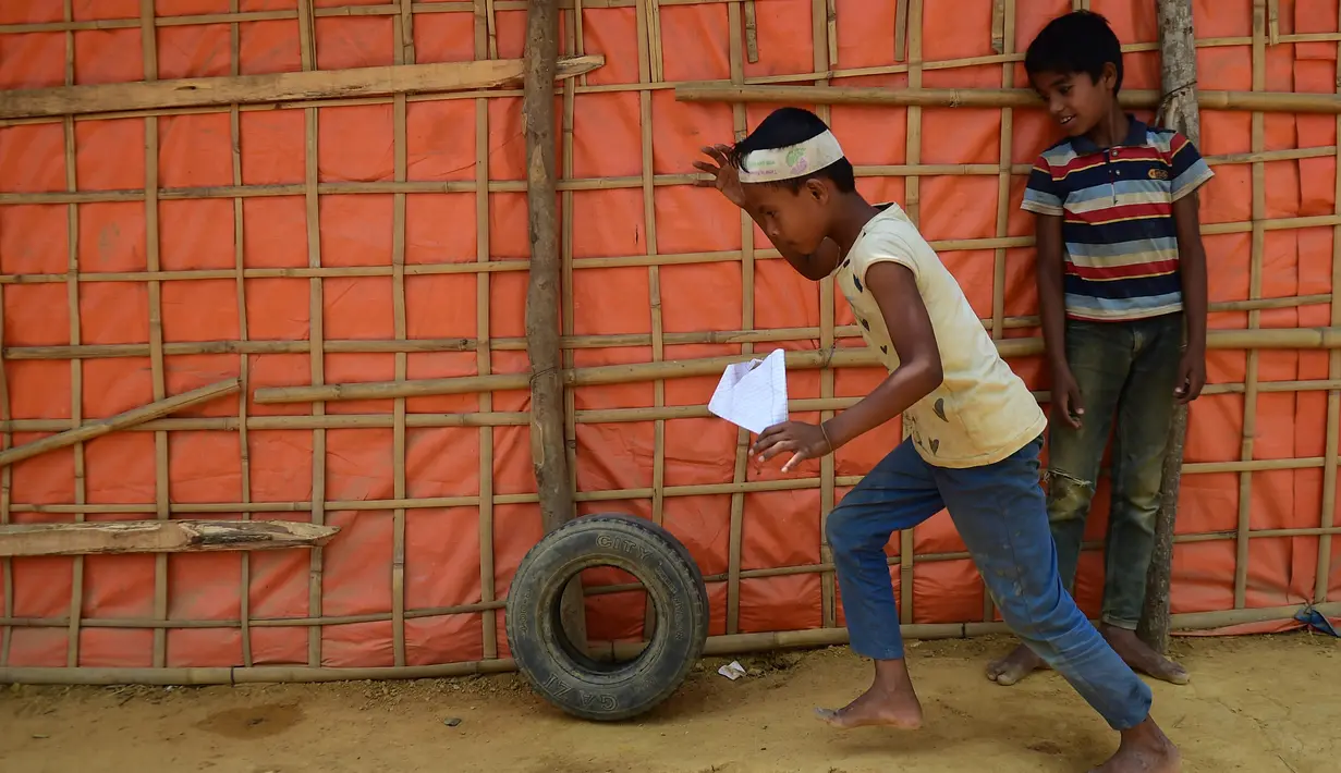 Dua bocah laki-laki bermain di sekitar kamp pengungsi Kutupalong, Bangladesh (5/4). Pemerintah Bangladesh mengatakan proses relokasi akan dilakukan dengan sukarela dari para pengungsi. (AFP Photo/Munir Uz Zaman)