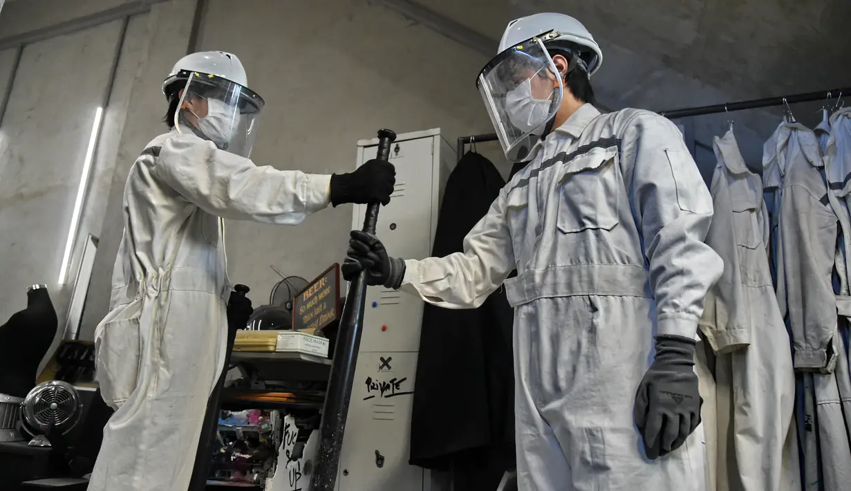 Dua orang pria mengambil tongkat pemukul Baseball di "rage room" atau ruang kemarahan di Singapura (19/10). Para karyawan bisa melampiaskan kemarahan mereka dengan memukul, melempar barang-barang dari botol hingga televisi. (AFP Photo/Roslan Rahman)