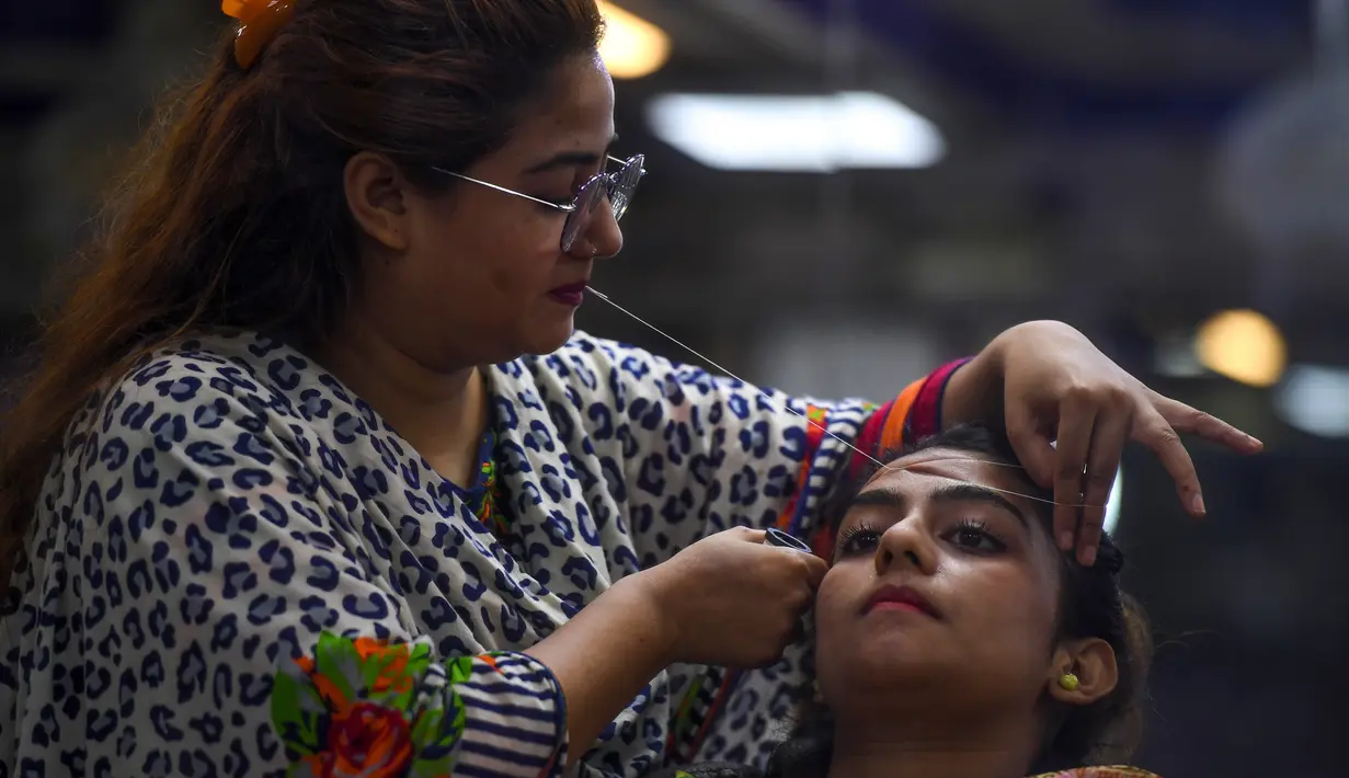 Ahli kecantikan membersihkan rambut di wajah seorang wanita menjelang  Hari Raya Idul Fitri di Karachi (3/6/2019). Umat Muslim di seluruh dunia sedang bersiap untuk merayakan Hari Raya Idul Fitri, yang menandai akhir bulan puasa Ramadan. (AFP Photo/Asif Hassan)