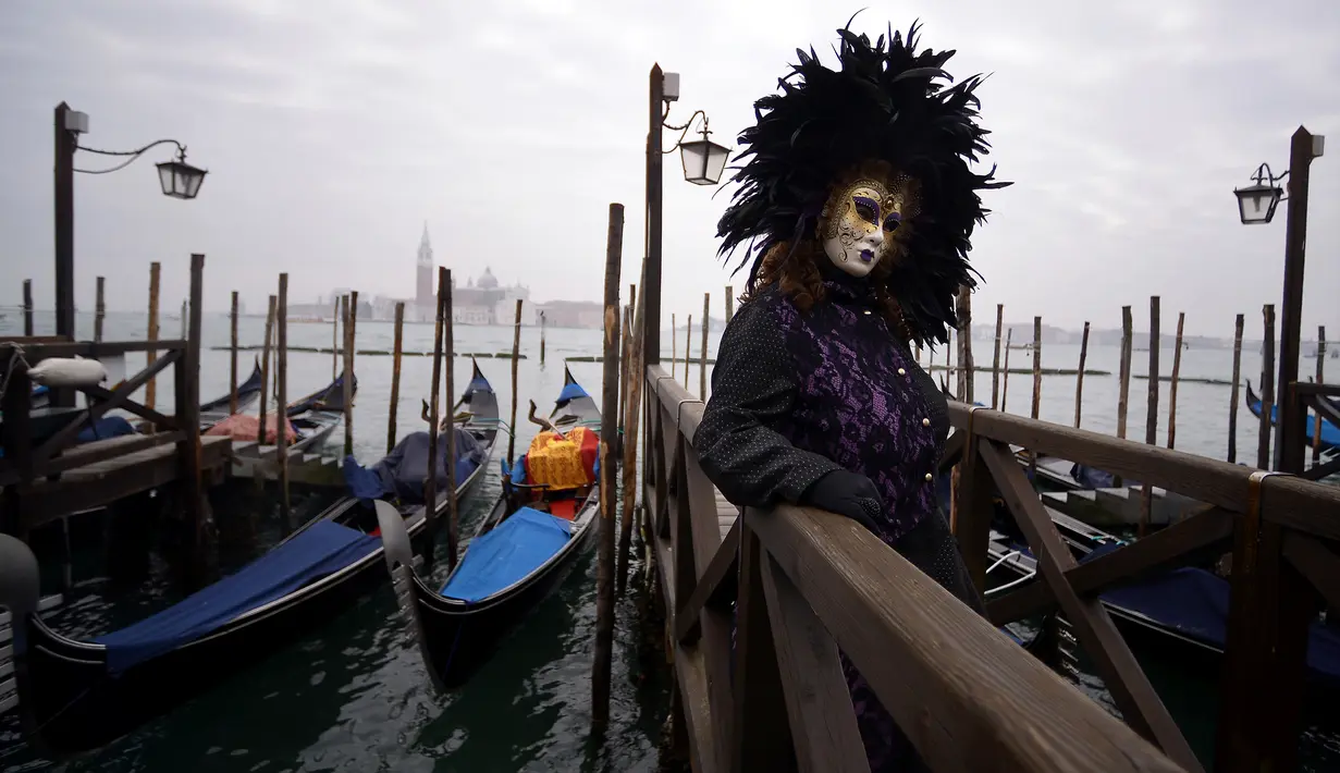 Peserta mengenakan kostum dan topeng berpose untuk difoto saat berpartisipasi dalam Karnaval Venesia di Italia (27/1). Karnaval Venesia adalah festival yang rutin diadakan setiap tahunnya di kota Venesia, Italia. (AFP Photo/Filippo Monteforte)