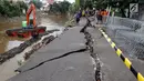 Petugas memperbaiki jalan retak di Kelurahan Kebon Manggis, Kecamatan Matraman, Jakarta Timur, Jumat (16/2). Retakan jalan bertambah panjang sekitar 25 meter setelah beberapa hari sebelumnya mengalami retakan sekitar 100 meter. (Liputan6.com/Johan Tallo)