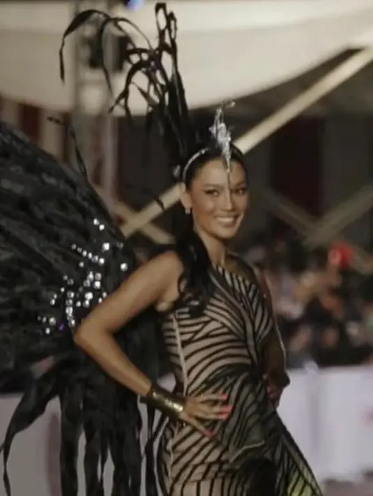Erika Carlina tampak elegan saat catwalk di depan publik mengenakan one shoulder dress nuansa abu-abu dan hitam, ditambah dengan sayap dramatis. [Instagram/eri.carl]