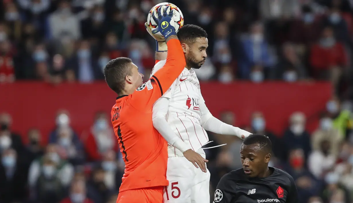 Kiper Lille Ivo Grbic (kiri) menangkap bola di sebelah penyerang Sevilla, Youssef En-Nesyri pada babak lanjutan Grup G Liga Champions di stadion Ramon Sanchez Pizjuan, Rabu (3/11/2021) dinihari WIB. Sevilla tumbang 1-2 di tangan Lille. (AP Photo/Angel Fernandez)