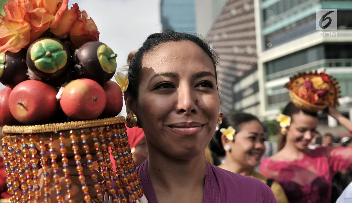 Mahasiswa internasional dengan balutan pakaian adat Indonesia membawa berbagai macam buah-buahan saat pawai kelulusan beasiswa Kemendikbud di car free day (CFD), Jakarta, Minggu (6/5). (Merdeka.com/Iqbal Nugroho)