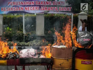 Petugas membakar barang bukti tindak pidana umum di lapangan Kejaksaan Negeri Jakarta Barat, Selasa (11/12). Barang bukti yang dimusnahkan berupa senjata Api, psikotropika, makanan, obat-obatan dan kosmetika. (Liputan6.com/Faizal Fanani)