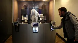 Seorang pelanggan mengambil kopi yang dibuat oleh robot barista di Cafe X, San Francisco, California, AS, Selasa (12/2). Cafe X memiliki robot yang mampu membuat tiga gelas kopi dalam 40 detik. (Justin Sullivan/Getty Images/AFP)