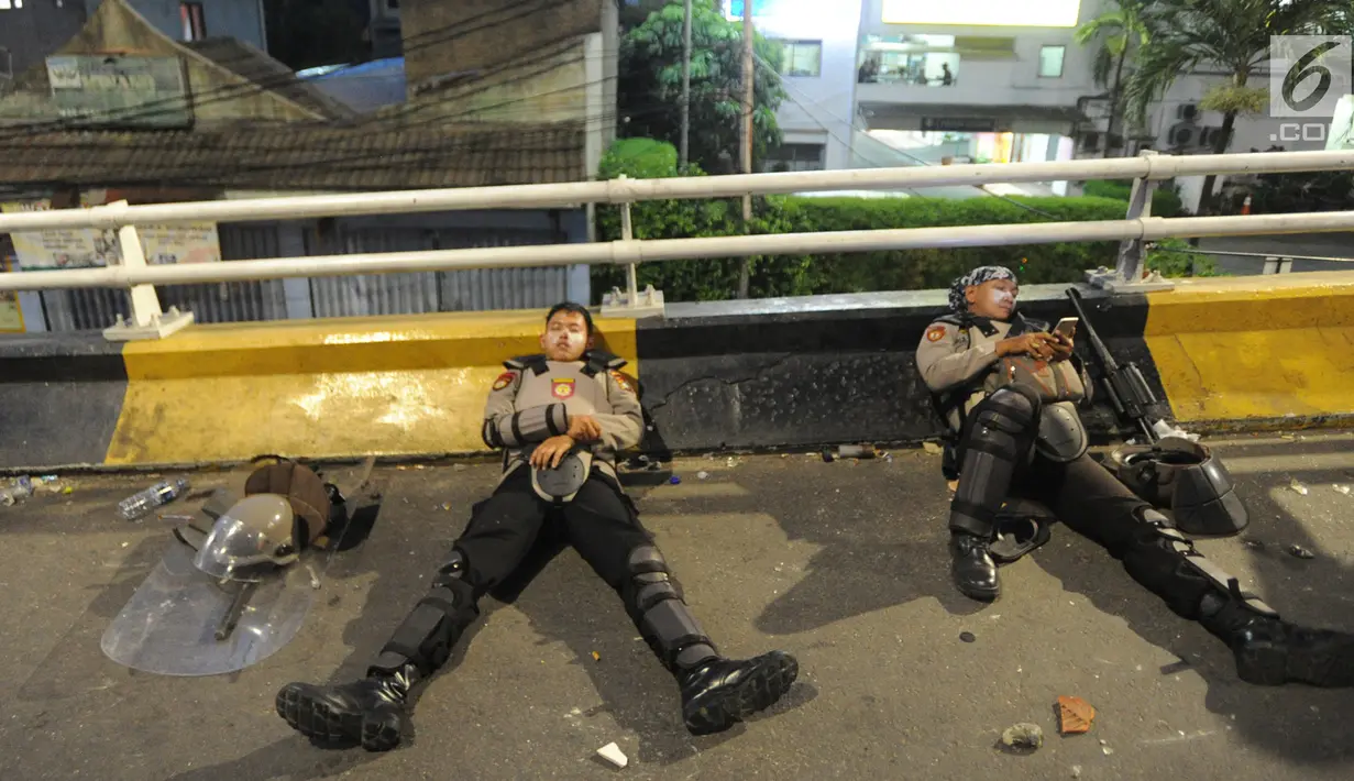 Anggota Dalmas BKO dari Polda Bali beristirahat usai mengamankan perusuh di atas fly over Slipi, Jakarta, Rabu (22/5/2019). Bentrokan panjang dengan para perusuh membuat anggota kepolisian yang berhadapan langsung kurang beristirahat. (merdeka.com/Arie Basuki)
