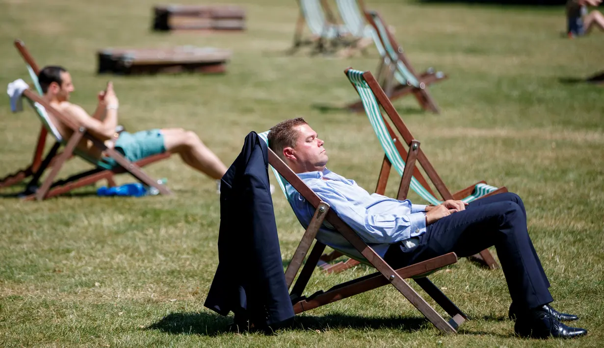 Seorang warga Inggris berjemur di atas kursi sambil menikmati sinar matahari di Green Park, London, Senin (25/6). Pada Juli 2018, suhu di ibu kota London tercatat 29.1 derajat Celcius dan diprediksi akan mencapai 30 derajat Celcius. (AFP/Tolga Akmen)