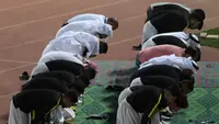 Para pemain Timas Qatar salat berjamaah sebelum sesi latihan mereka di Abu Dhabi (31/1). Qatar harus melewati Korea Selatan sebelum menginjakkan kakinya di final Piala Asia 2019. (AFP Photo/Roslan Rahman)