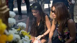 Dua orang turis Jerman ikut berdoa di dekat Kuil Erawan yang sempat ditutup karena peristiwa ledakan bom pada Senin (17/8), Bangkok, Rabu (19/8/2015). Peristiwa tersebut dikabarkan telah menewaskan sekitar 20 orang. (AFP Photo/Jerome Taylor)