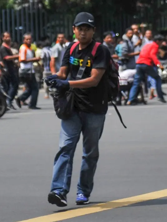 Terlihat seorang pria membawa senjata di Jalan Thamrin, Jakarta, Kamis (14/1). Dari foto, terlihat seorang pria berkaos hitam, topi hitam dan memakai sarung tangan tengah memegang senjata api. (REUTERS/Veri Sanovri/Xinhua)