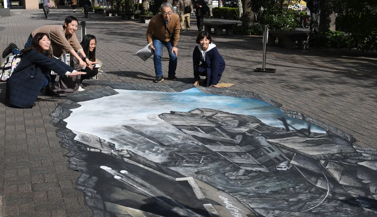 Sejumlah warga berpose untuk berfoto di depan karya ilusi optik 3-D yang bergambar kota Aleppo yang hancur akibat perang di kampus Universitas Meiji di Tokyo, Jepang (18/11). (AFP/Toshifumi Kitamura
