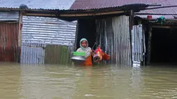 Seorang wanita membawa peralatan rumah tangga saat meninggalkan rumahnya yang terendam banjir di Sunamganj, Bangladesh, Minggu (12/7/2020). Banjir di sejumlah wilayah Bangladesh telah memengaruhi kehidupan lebih dari 1,3 juta orang dan mengakibatkan puluhan ribu keluarga mengungsi. (Xinhua)