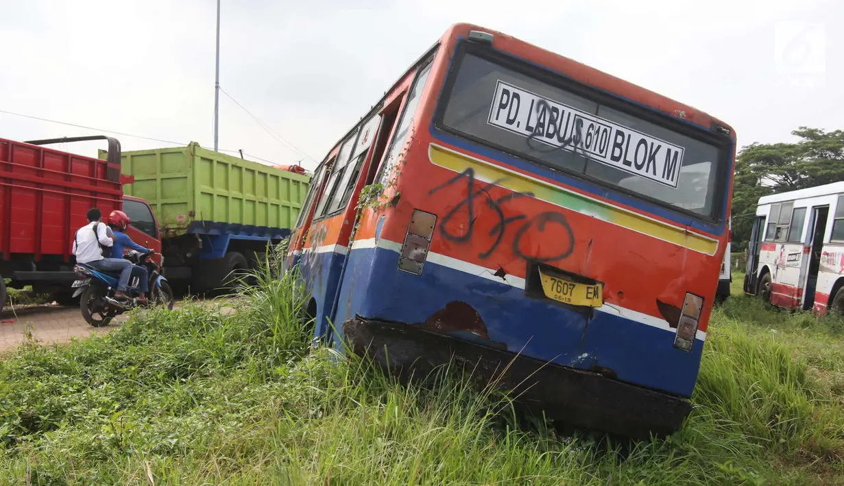 Pengendara motor melintas disamping bus Metromini di Pool Bus Dinas Perhubungan DKI Jakarta, Rawa Buaya, Jumat (23/3). Bus Metromini yang rusak dan tak layak mulai digantikan oleh angkutan umum Minitrans dan Metrotrans. (Liputan6.com/Arya Manggala)