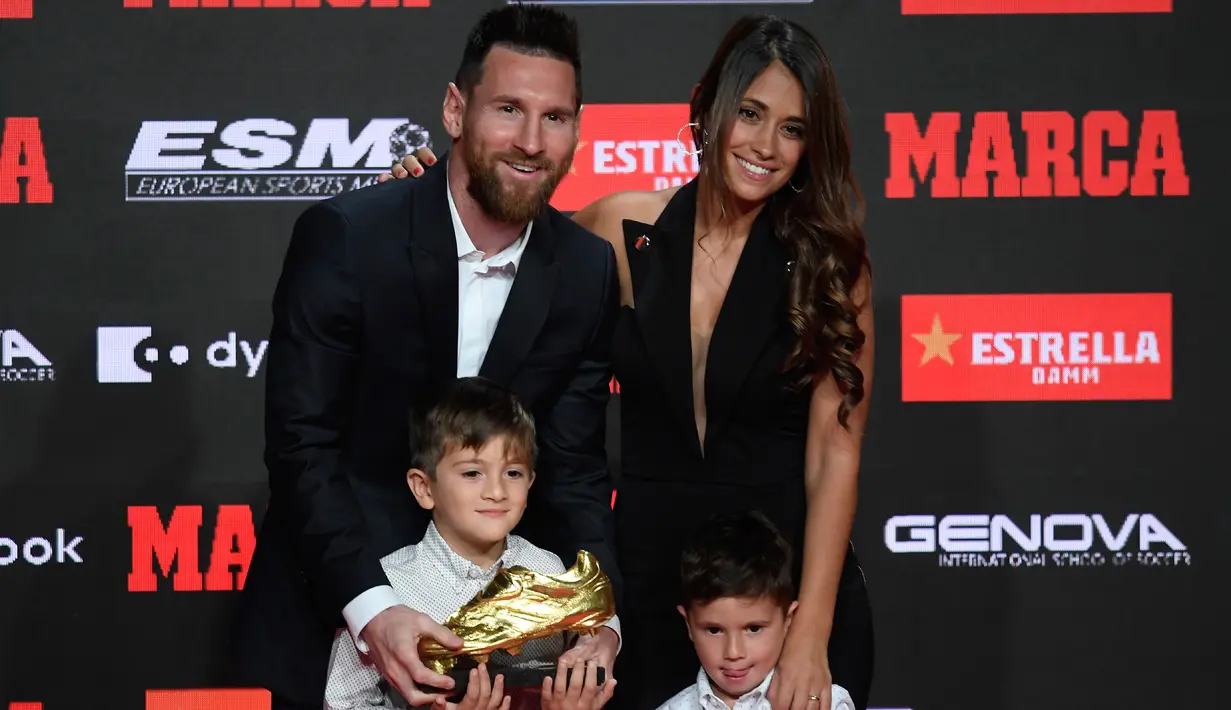 Pemain Barcelona, Lionel Messi didampingi istrinya Antonella Roccuzzo dan kedua putranya berpose setelah menerima trofi Sepatu Emas keenamnya selama acara penyerahan di Antiga Fabrica Estrella Damm, Barcelona, Spanyol (16/10/2019). (AFP Photo/Josep Lago)