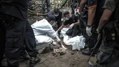 Tim forensik Malaysia memeriksa tubuh manusia yang baru digali dari sebuah makam tak bertanda di Bukit Wang Burma, dekat perbatasan Malaysia-Thailand, (26/5/2015). 139 kuburan massal yang berisi kerangka orang ditemukan.  (AFP PHOTO/MOHD RASFAN)