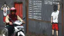 Pengendara sepeda motor melintas di depan mural anti korupsi bertuliskan 'I promise i'll learn not corruption' atau "Saya berjanji saya akan belajar untuk tidak korupsi" di Jakarta, Minggu (05/03). (Liputan6.com/Helmi Afandi)