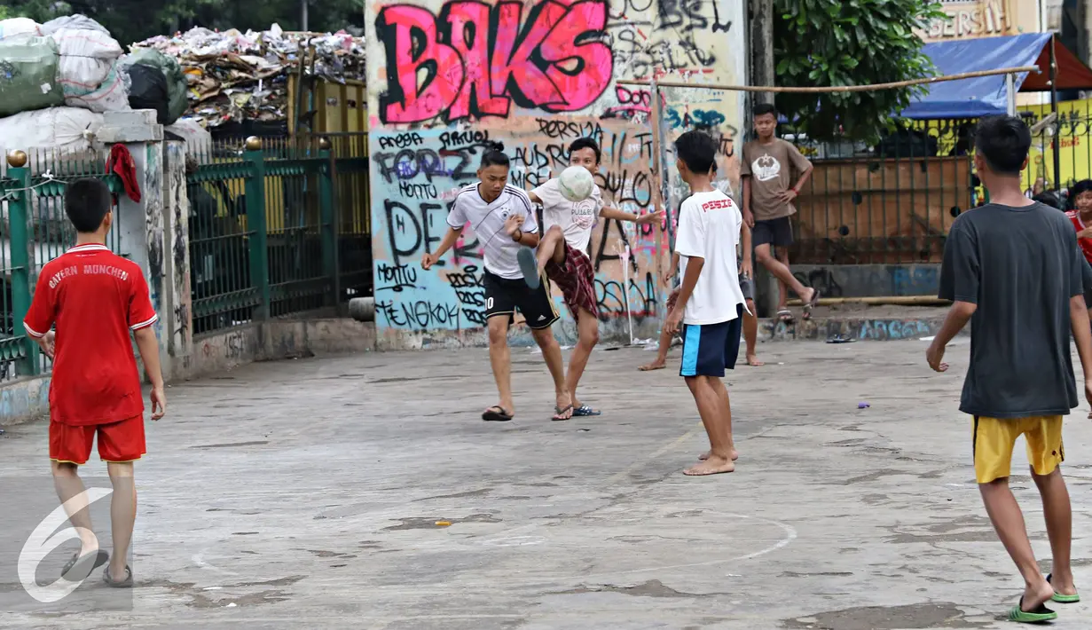 Sejumlah remaja berebut bola saat bermain di kolong rel kereta kawasan Juanda, Jakarta, Jumat (27/5). Tidak tersedianya ruang terbuka menyebabkan lahan tersebut dijadikan tempat bersosialisasi bagi warga. (Liputan6.com/Immanuel Antonius)